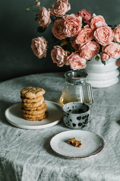 pink flowers beside plate of biscuits